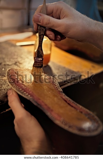Shoemaker makes shoes for men.\
He smears special\
liquid  with a brush.