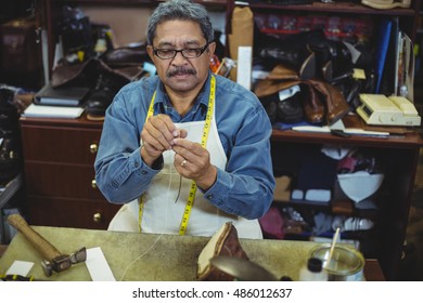 Shoemaker putting thread in the needle in workshop