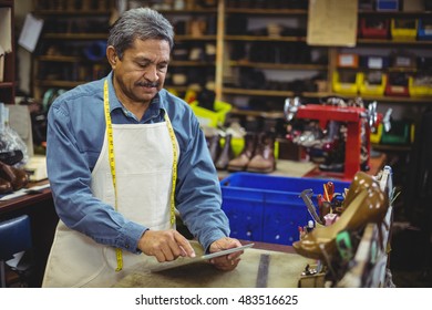 Shoemaker using digital tablet in workshop - Powered by Shutterstock