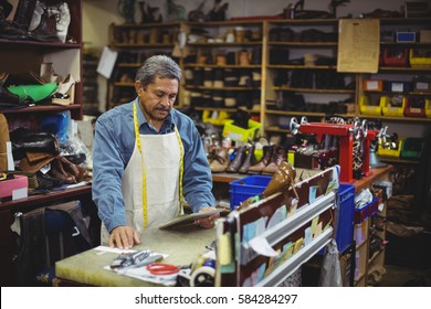 Shoemaker using digital tablet in workshop - Powered by Shutterstock