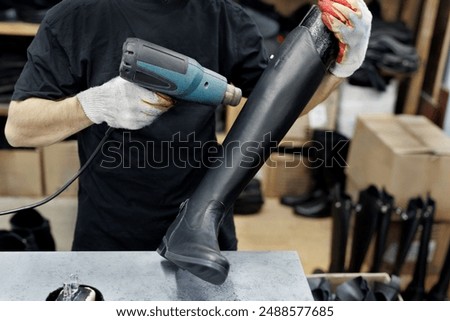 Shoemaker warms up the skin when making boots. A shoemaker works in his workshop at a shoe factory