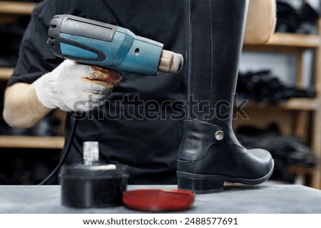 Shoemaker warms up the skin when making boots. A shoemaker works in his workshop at a shoe factory