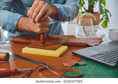 Shoemaker working leather in a workshop using a stamp, small business and craftsmanship concept
