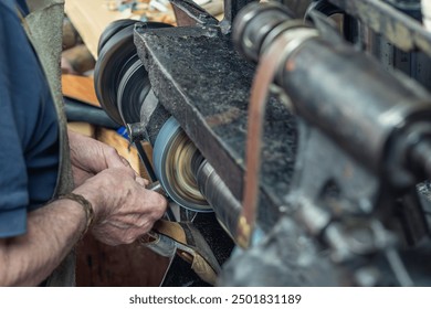 Shoemaker's hands that pass the sole of a shoe through the polisher to shape it. Concept: artisan trades and small commerce. Sustainability, circular economy, savings and ecology - Powered by Shutterstock