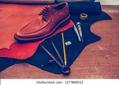 Shoemaker's work desk. Tools and leather at cobbler workplace. Man classic brown shoes and leather shoemaking tools and set of leather craft tools . Shoes maker tools on wooden table - Powered by Shutterstock