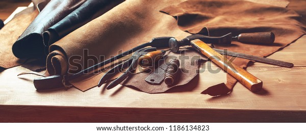 Shoemaker\'s work desk. Tools and leather at cobbler\
workplace. Set of leather craft tools on wooden background. Shoes\
maker tools on wooden\
table