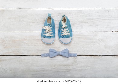 shoes and a butterfly-tie for the boy on a wooden background. View from above