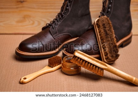 Shoes Cleaning Accessories for Dark Brown Grain Brogue Derby Boots Made of Calf Leather Over Paper Background with Cleaning Tools. Horizontal Composition