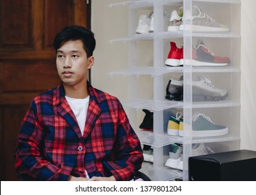 Shoes Collector Sitting Next To His Sneakers Collection