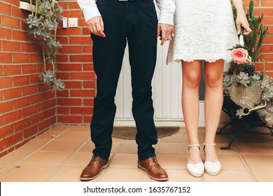 Shoes of groom and bride and her small wedding bouquet of pink roses with clasped hands after the ceremony. Wedding concept. Wedding day and newlyweds concept. - Powered by Shutterstock