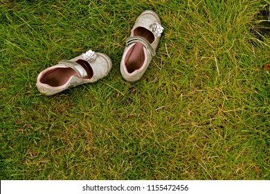Shoes left in the grass - little girls shoes abandoned by a playing child in the grass. - Shutterstock ID 1155472456