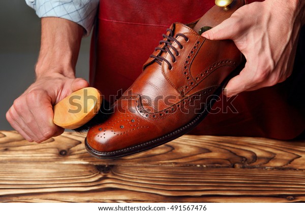 Shoes\
master (man) polishing leather shoes with\
brush