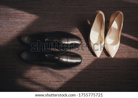 Shoes men and women on the floor with light and shadows from the window. Black and white shoes are newlyweds. Bride and groom morning concept