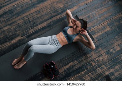 Shoes on the side. Top view of girl with slender body works on the abs when lying on the floor.