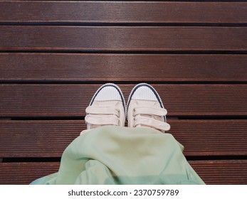 Shoes selfie from above covered by a long dress with a wooden background. High angle view.