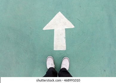  shoes standing on the concrete floor and white direction sign to go ahead - Shutterstock ID 468991010