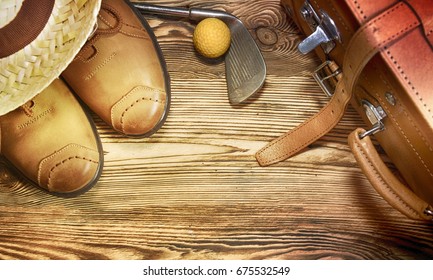 Shoes, straw hat, golf ball on the wooden background