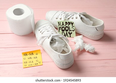 Shoes With Toilet Paper And Happy Fools' Day Note On Pink Wooden Background