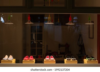 Shoes in a window display of a shoemaker workshop at night. A cobbler sewing machine is visible in the background. - Powered by Shutterstock