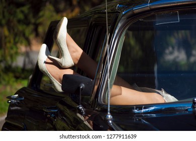 shoes from window old car. couple taking off on their honeymoon after the wedding ceremony. Legs of girl. bride in high heels shoes in window