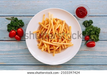 Shoestring French Fries with bbq sauce, Sea Salt and tomatoes in white plate on wooden table background top view side dish