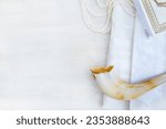 A shofar, tallit and siddur book on a white background. photographed from above.   A symbol of the Rosh Hashanah holiday. Suitable for shana tova greeting card and Yom Kippur.
with free space for text