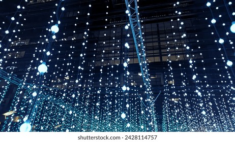 Shoot from below to multiple strips of blue LED lightbulbs hanging from railings at night during the Canary wharf winter lights festival in 2024