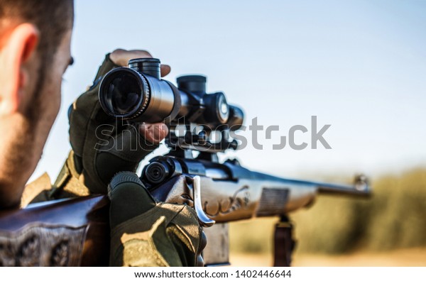 Shooter sighting in the target. The man is on the hunt.\
Hunt hunting rifle. Hunter man. Hunting period. Male with a gun.\
Close up. Hunter with hunting gun and hunting form to hunt. Hunter\
is aiming. 