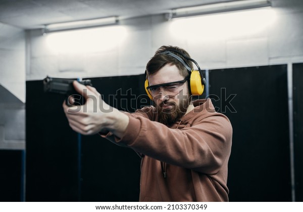 Shooting in the dash of short-barreled weapons. A man\
aims at a target before firing a pistol. special ballistic\
headphones controls 