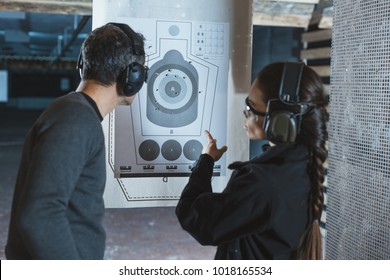 shooting instructor pointing on used target in shooting range