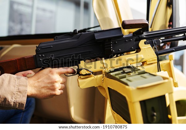 Shooting a machine gun\
during the battle. The hand of a military man on the trigger of a\
military weapon. Fragment of a yellow vehicle for battles in a\
sandy area. Close-up