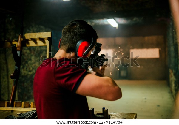 Shooting a pistol at target in indoor firing range\
or shooting range