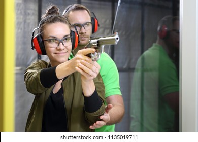 Shooting Range. Shooting With A Gun. The Woman Shoots From The Gun At The Shooting Range Under The Supervision Of An Instructor.