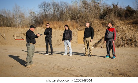 Shooting range instructor demonstrate gun shoot techniques to group of his students. Civilian team weapons training