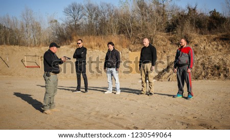 Shooting range instructor demonstrate gun shoot techniques to group of his students. Civilian team weapons training