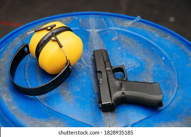 Shooting Range. Protective Earmuffs And A Gun Lie On The Table