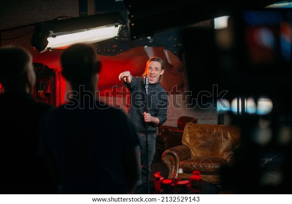 Shooting a
stand-up show. Stand-up comedian on stage at the microphone. A
young man, an author of jokes and comedy texts, stands on a stage
in a studio during the filming of a
show.
