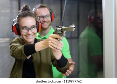 Shooting Training.  Die Frau schießt unter der Aufsicht eines Instruktors aus der Pistole auf den Schießstand.