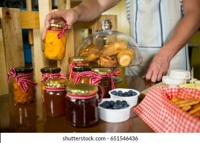 Shop assistant arranging jam and pickle jars in grocery shop - Powered by Shutterstock