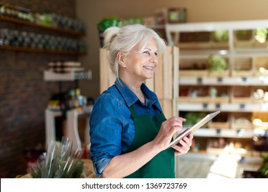 Shop assistant with digital tablet in small grocery store - Powered by Shutterstock