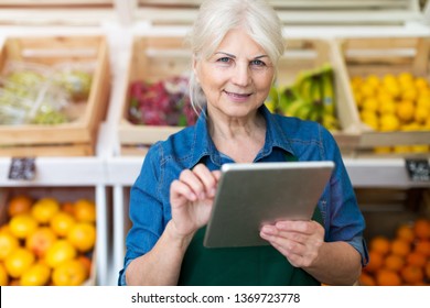 Shop Assistant With Digital Tablet In Small Grocery Store