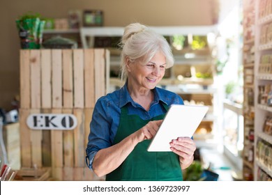 Shop assistant with digital tablet in small grocery store - Powered by Shutterstock