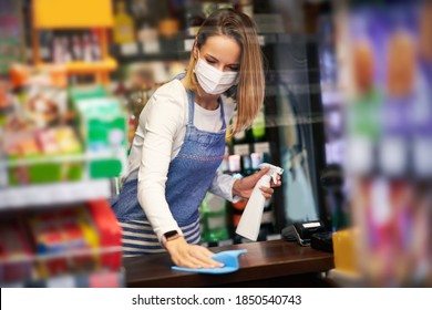 Shop assistant disinfecting surfaces in grocery store - Powered by Shutterstock