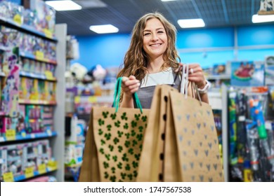 Shop Assistant Give Shopping Bags To A Female Customer. Attractive Woman Shop Keeper Giving Paper Bag To Buyer.