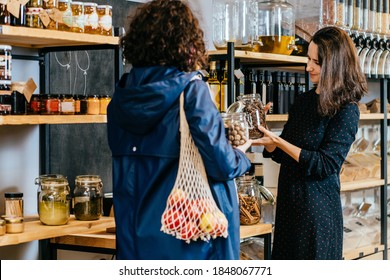 Shop assistant helping customer in bulk food store. Seller advising woman in her purchase of groceries without plastic packaging in zero waste shop. Sustainable shopping at small local businesses. - Powered by Shutterstock