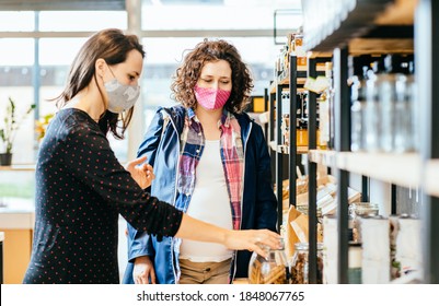 Shop Assistant Helping Pregnant Woman In Bulk Food Store. Seller Advising Customer In Her Purchase Of Groceries Without Plastic Packaging In Zero Waste Shop. Support Small Local Businesses.