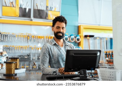 Shop assistant of retail store. Confident Bearded african american man at counter with big smile in hardware store