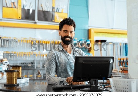 Shop assistant of retail store. Confident Bearded african american man at counter with big smile in hardware store