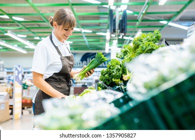 Shop Assistant In Supermarket Re-stocking Fresh Vegetables Into Boxes