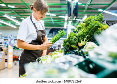 Shop assistant in supermarket re-stocking fresh vegetables into boxes - Powered by Shutterstock